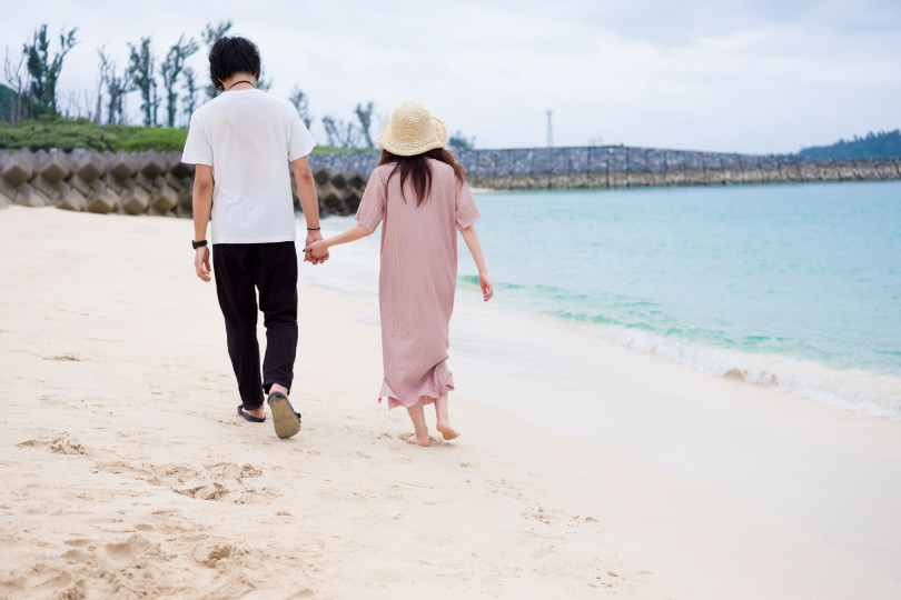 海辺を歩く夫婦
