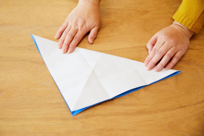 包装紙を開き、今度は柄のある面を表にして三角形に折る。