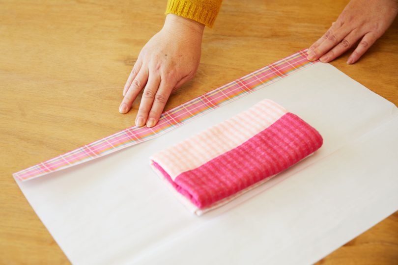 中央にタオルを置き、自分から見て包装紙の右側を3～5cmほど内側に折る。